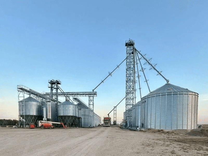 Grain yard with galvanized support towers carrying catwalks and conveyors between bins